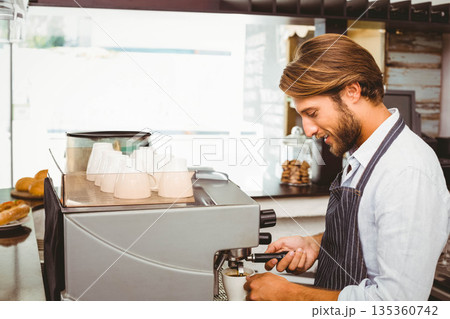 Male barista wearing striped apron and operating espresso machine at cafe with pastries, copy space Male barista wearing striped apron and operating espresso machine at cafe with pastries, copy space 135360742