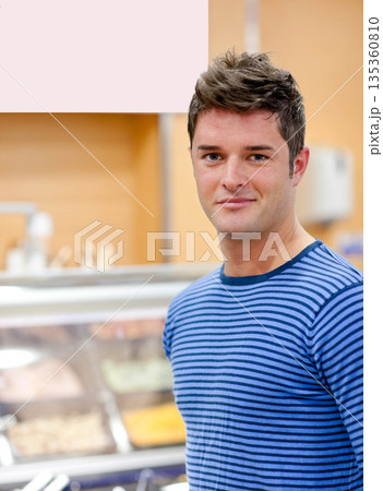 Man standing at cafeteria counter with glass sneeze guard, metal trays and utensils, copy space Man standing at cafeteria counter with glass sneeze guard, metal trays and utensils, copy space 135360810