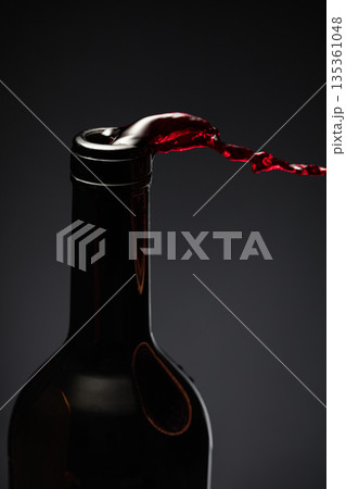 Red wine pours out of the bottle. 135361048