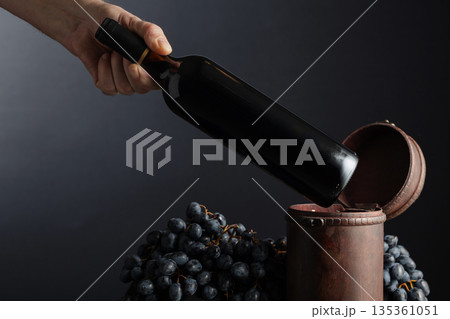 Sommelier places a bottle of red wine in an old wooden box. 135361051