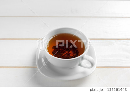 Fresh tea in a white cup on a wooden table in a simple indoor setting 135361448