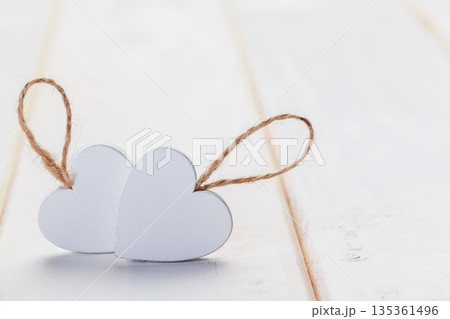 Hearts made of paper on a wooden surface with strings tied to them 135361496