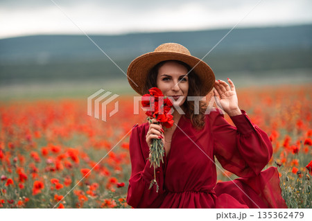 Woman poppy field portrait of a young woman wearing a straw hat and red dress Woman poppy field portrait of a young woman wearing a straw hat and red dress 135362479