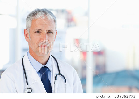Male doctor standing in clinic reception area wearing lab coat and stethoscope, copy space Male doctor standing in clinic reception area wearing lab coat and stethoscope, copy space 135362773