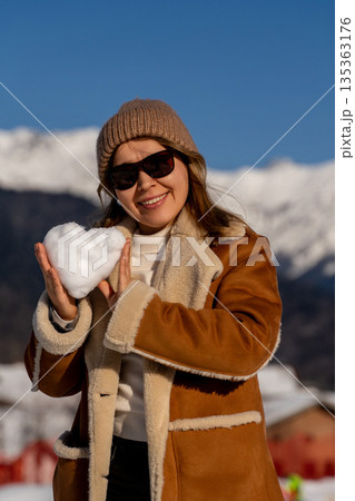 Snow Heart Woman Mountains: Winter Fun, Happy Woman Holds Snow Heart, Sunny Day. Snow Heart Woman Mountains: Winter Fun, Happy Woman Holds Snow Heart, Sunny Day. 135363176