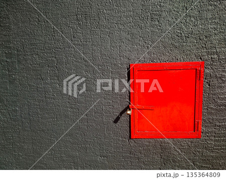 Bright Red Door Set Into Dark Textured Wall Creates Bold Industrial Contrast Bright Red Door Set Into Dark Textured Wall Creates Bold Industrial Contrast 135364809