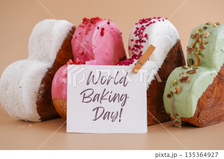 World baking day greeting card Delicious fresh croissant topped with colorful flavor Ganache. Creation unique heart shape bakery. Puff pastry holiday love gift present idea 135364927