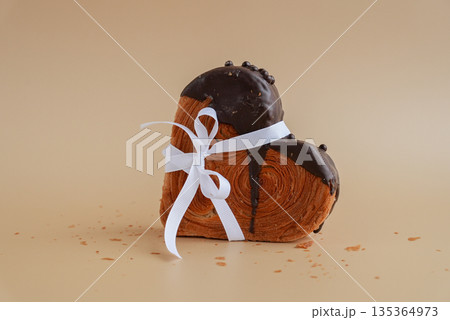 Present gift tied bow holiday Valentine's Day birthday celebration Heart shaped dark chocolate croissant on beige background with copy space. Puff pastry new trendy sweet dessert bakery. Creamy dough Present gift tied bow holiday Valentine's Day birthday celebration Heart shaped dark chocolate croissant on beige background with copy space. Puff pastry new trendy sweet dessert bakery. Creamy dough 135364973