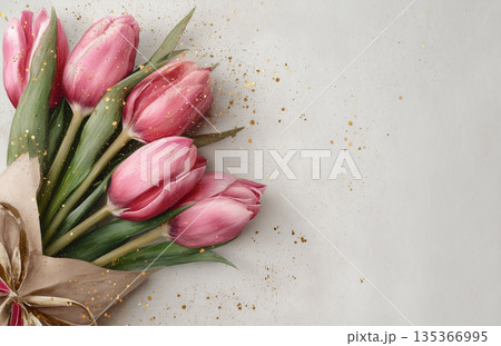 Fresh pink tulips arranged in a simple bouquet with decorative elements on a light background Fresh pink tulips arranged in a simple bouquet with decorative elements on a light background 135366995