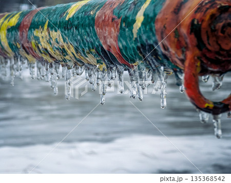 Close-up of a colorful metal fence coated in ice and frost. 135368542