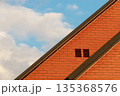 Part of the roof of a red brick house and blue sky 135368576