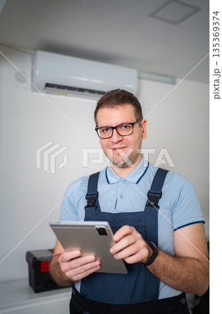 HVAC technician smiling holding digital tablet checking air conditioner 135369374