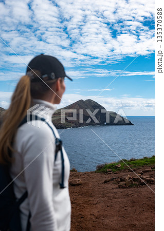 Female explorer observes distant coastal scenery serenely 135370588