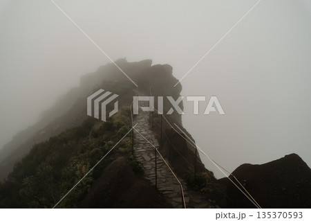 Eerie mountain landscape featuring rocky formations and thick fog Eerie mountain landscape featuring rocky formations and thick fog 135370593