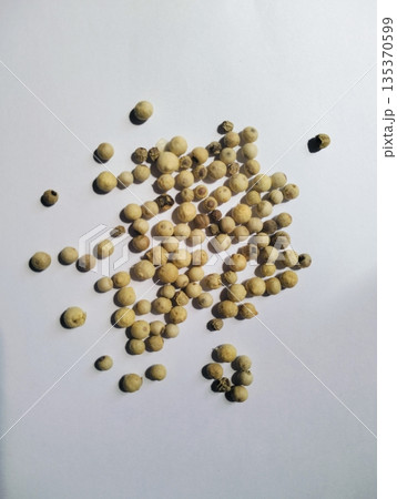 Dried white peppercorns isolated on white board with close up detail showing natural spice texture and culinary seasoning concept 135370599
