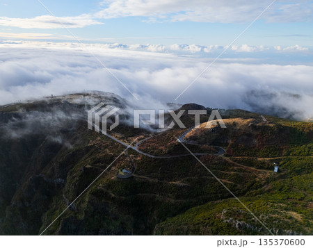 Marvelous aerial perspective of serpentine mountain road above clouds 135370600