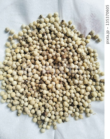 Dried white peppercorns isolated on white board with close up detail showing natural spice texture and culinary seasoning concept 135370605