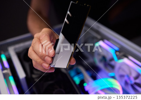 Upgrading computer with RGB lighting, Close up of hardware components during upgrade, Detailed view of installing RAM module into gaming computer with stylish lighting 135372225