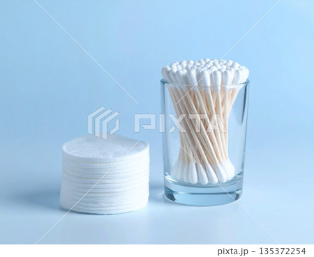 Sustainable packaging. White cotton swabs and reusable cotton pads neatly stacked on a white background. Sustainable packaging. White cotton swabs and reusable cotton pads neatly stacked on a white background. 135372254