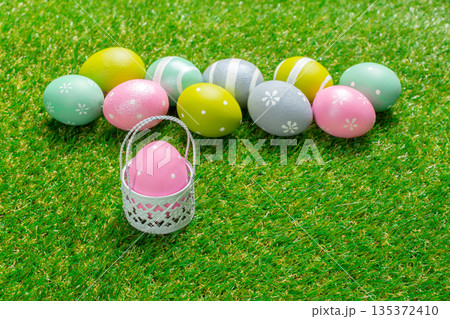 Colorful Easter eggs arranged on green grass with a small basket Colorful Easter eggs arranged on green grass with a small basket 135372410