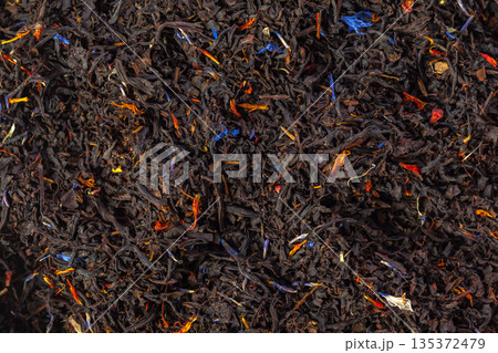 Dried black tea leaves mixed with orange and blue petals on a flat surface Dried black tea leaves mixed with orange and blue petals on a flat surface 135372479
