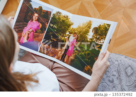 woman is holding and flipping through a photo book with a pregnancy photo shoot 135372492