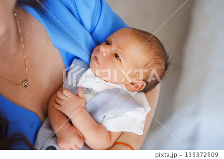 Newborn baby held by parent in soft clothing at home Newborn baby held by parent in soft clothing at home 135372509