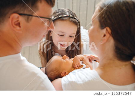 Family gathers around newborn baby in warm setting Family gathers around newborn baby in warm setting 135372547