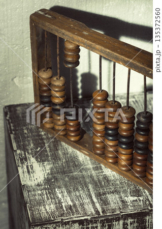 Wooden abacus on a rough table surface with a textured wall in the background 135372560