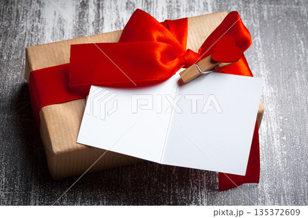 Gift box with red ribbon and card placed on wooden table 135372609