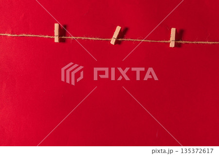 Red background with clothespins hanging on a string for art or craft activity 135372617