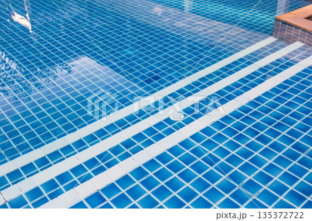 Bright blue swimming pool with tile design in warm sunny weather 135372722