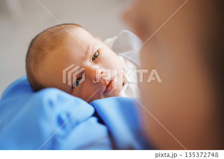 Newborn gazes at caregiver with soft expression 135372748