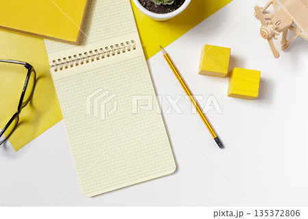 Notepad and stationery items on a white surface with yellow accents in the workspace Notepad and stationery items on a white surface with yellow accents in the workspace 135372806