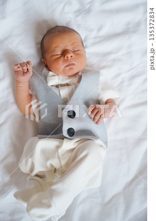 Baby boy in a vest lying on a white blanket 135372834