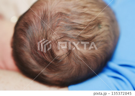 Close view of baby's head on caregiver's arm 135372845