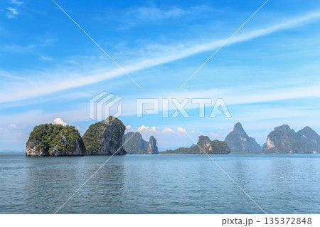 Islands rise from calm water under bright blue sky in a beautiful landscape scene 135372848