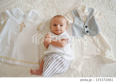 Baby surrounded by outfits for special occasion Baby surrounded by outfits for special occasion 135372861