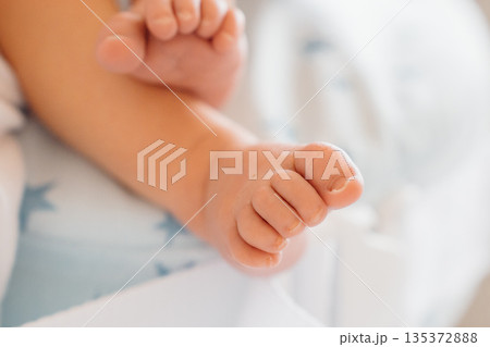 Baby feet resting on a soft blanket in a bright room Baby feet resting on a soft blanket in a bright room 135372888
