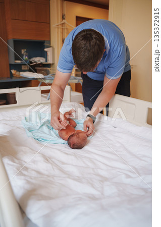 Father cares for newborn in hospital room setting 135372915