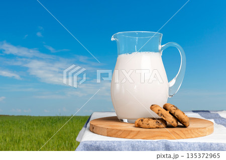 Milk and cookies sit on a table in a field under a blue sky during the day Milk and cookies sit on a table in a field under a blue sky during the day 135372965