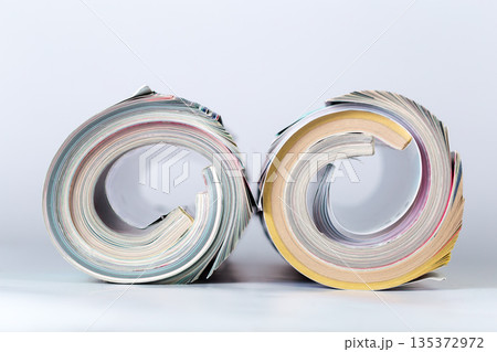 Piles of rolled magazines arranged side by side on a plain background at a studio 135372972
