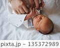 Newborn baby being cared for by adult hands 135372989