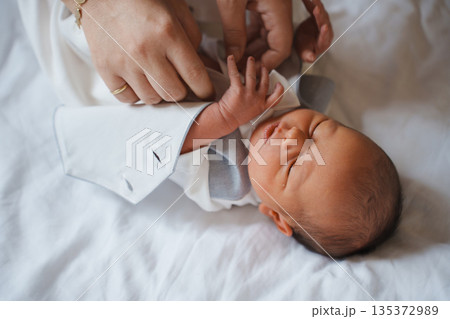 Newborn baby being cared for by adult hands 135372989