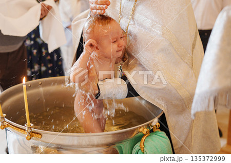 Baptism ceremony with a baby being baptized in water 135372999