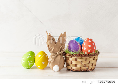 Colorful eggs and a bunny figure in a woven basket for spring celebrations 135373039
