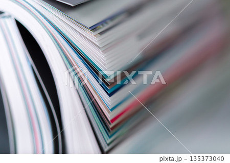 Stacked pages from various magazines showing different colors and textures on a table 135373040