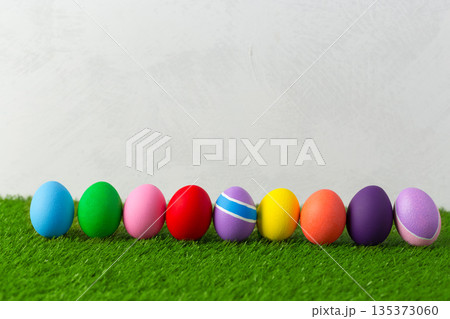 Colorful eggs lined up on green grass for spring celebration or holiday event Colorful eggs lined up on green grass for spring celebration or holiday event 135373060