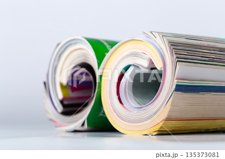 Magazines rolled on a table with colorful pages and covers stacked together Magazines rolled on a table with colorful pages and covers stacked together 135373081