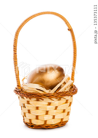 Golden egg placed in a woven basket filled with straw Golden egg placed in a woven basket filled with straw 135373111